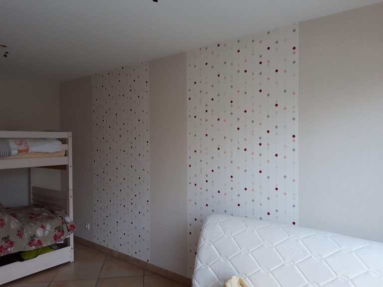 Chambre d'enfant : pan de mur en papier peint à pois colorés, près des lits superposés