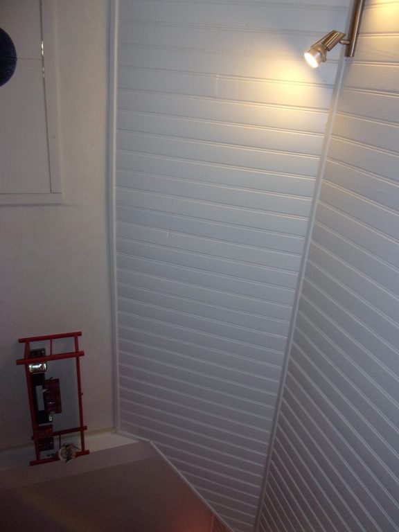 Pente de toit en lambris blanc éclairée par une applique