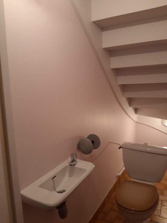 Lave-mains et paroi repeinte en rose poudré sous l'escalier