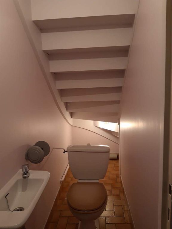 WC sous escalier vus depuis la porte, murs clairs et sol en tomettes