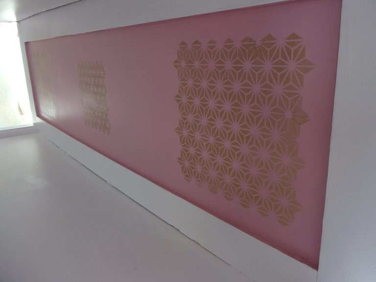 Détail d'un panneau rose orné d'un pochoir doré