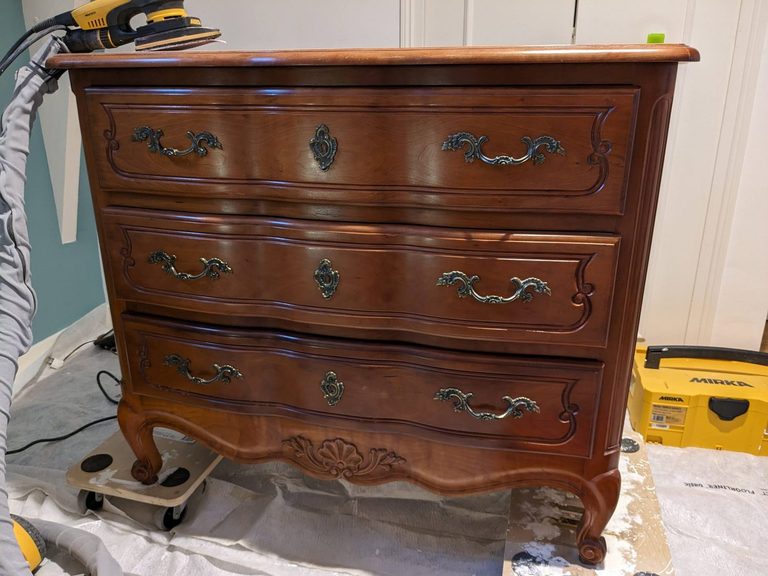La commode Louis XV avant relooking, bois verni foncé en cours de ponçage