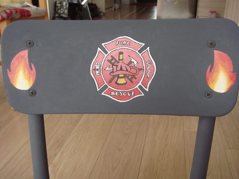 Dossier de la chaise : écusson de pompiers encadré de deux flammes
