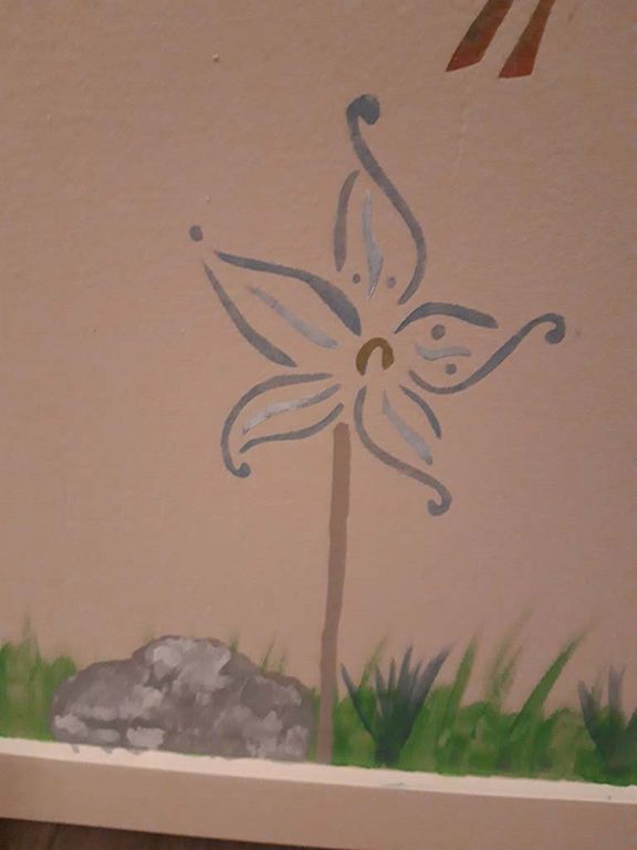 Détail du coffre : fleur stylisée bleu-gris sur fond crème