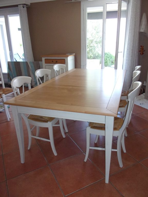 Table et chaises blanches devant la baie vitrée, sol en tomettes