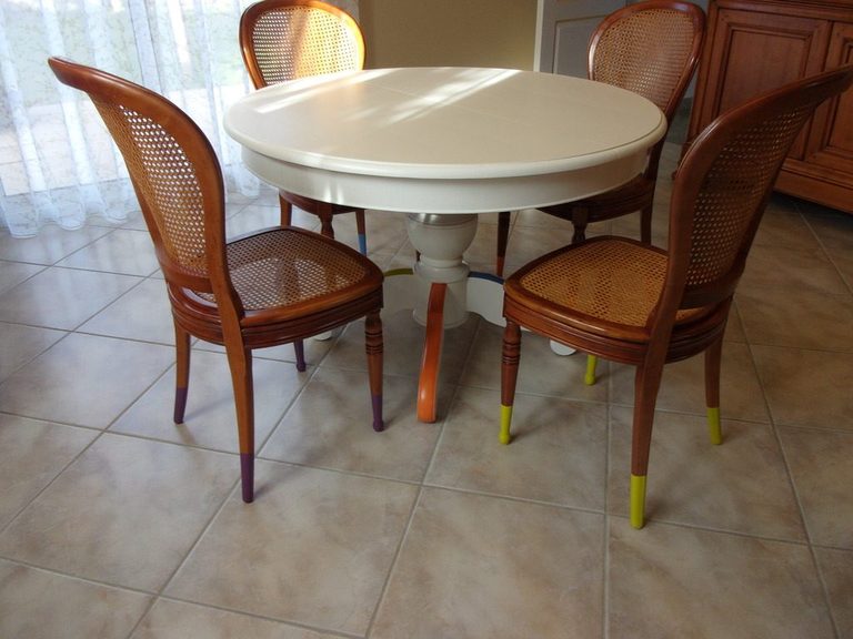 Table ronde repeinte entourée de ses chaises cannées